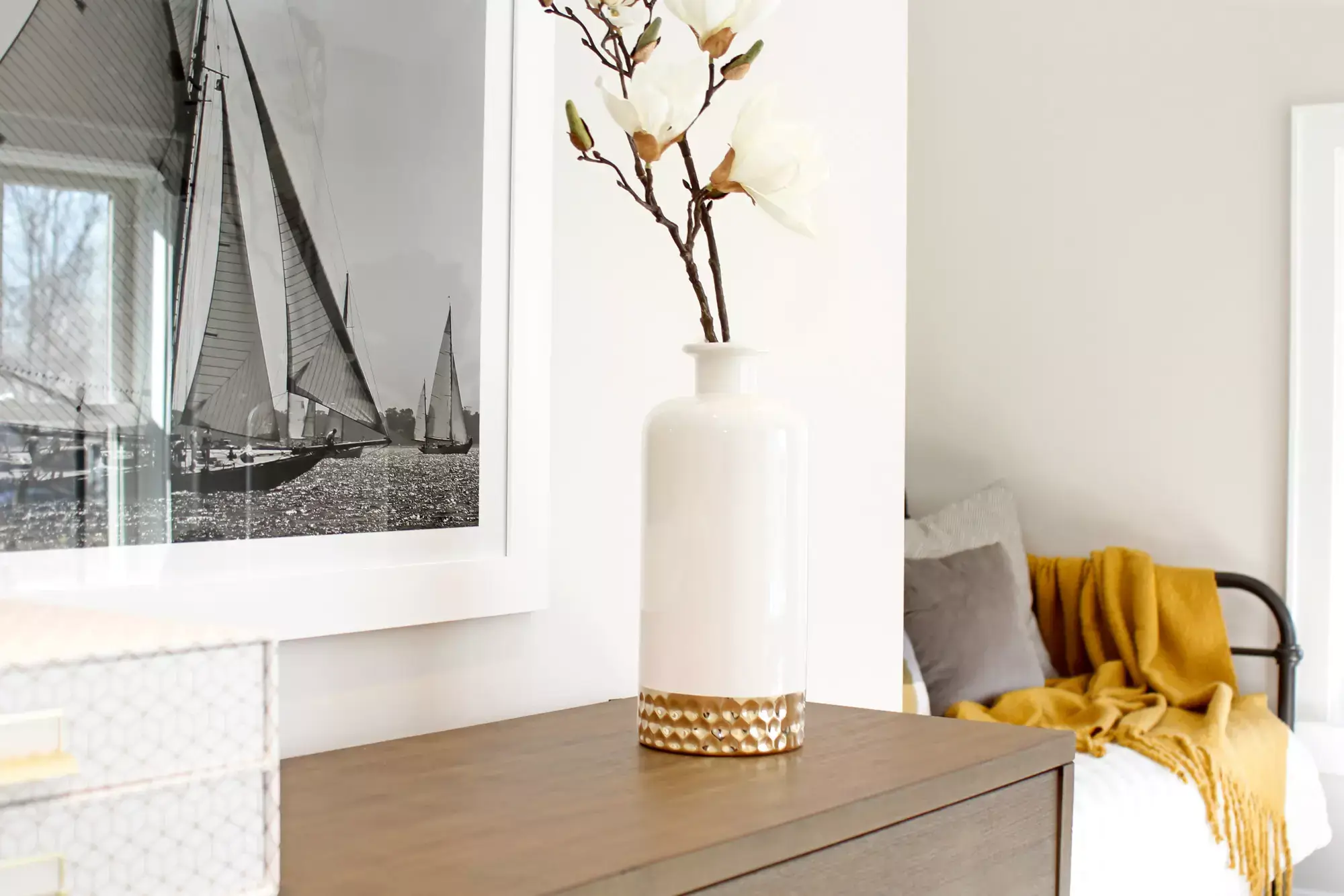 White flower vase on the wardrobe and a picture frame on the wall.