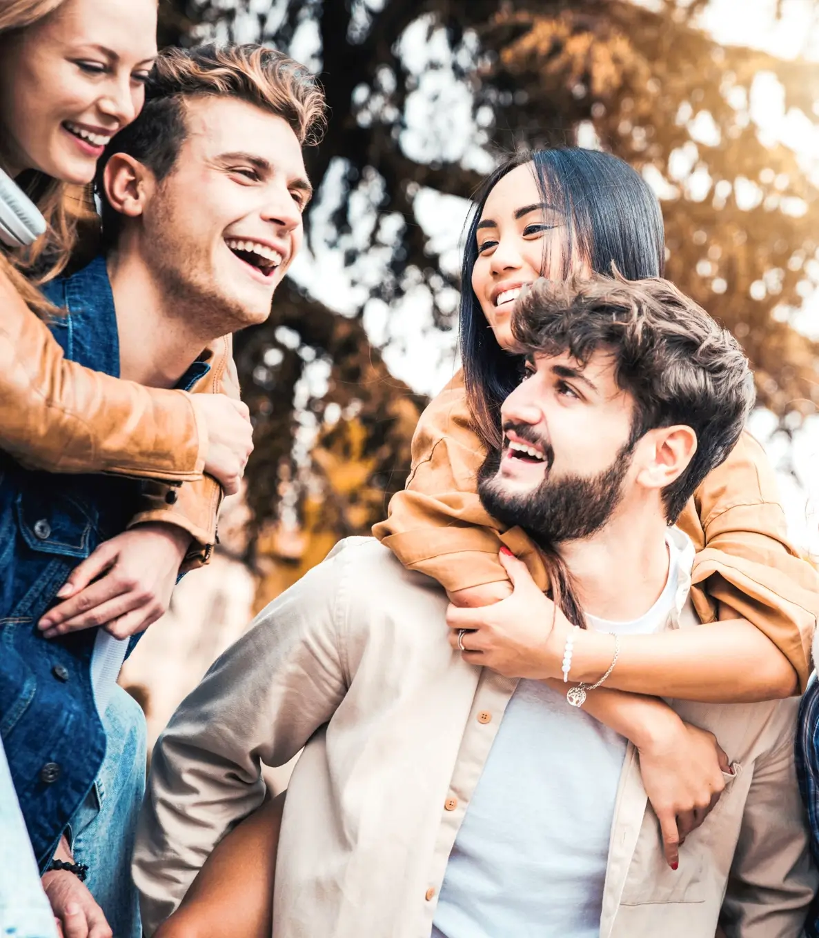 Millennials friends on vacation having piggyback race on city street - Young people group enjoying time together laughing outdoors - Summer vacations, friendship and happy lifestyle concept